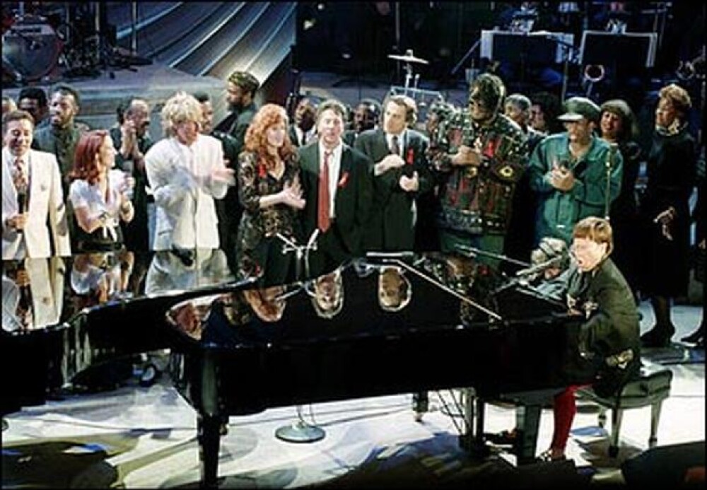 Elton John plays the piano as other performers take part in the finale of "Aretha Franklin: Duets," an AIDS benefit concert in New York on Tuesday, April 28, 1993. Standing, from left are, Smokey Robinson, Gloria Estefan, Rod Stewart, Bonnie Raitt, Dustin Hoffman, Robert De Niro and Prince Be of PM Dawn.